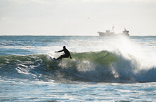 A Surfer Surfing On Large Wave In Front Of Fishing Boat, Rhode Island