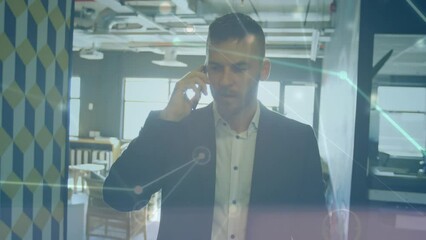 Poster - A businessman is talking on a mobile phone while walking through an office