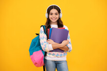 Schoolgirl, Teenage Student Lifestyle Girl In Headphones Hold Books On Yellow Isolated Studio Background. School And Music Education Concept.