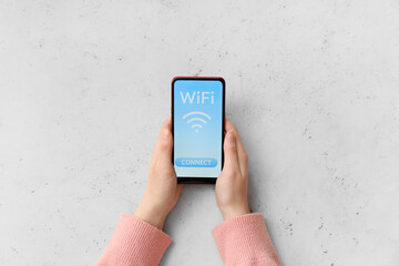 Wall Mural - Woman holding mobile phone with WiFi symbol and connection button on light background