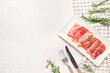 Plate with slices of tasty ham and rosemary on light background