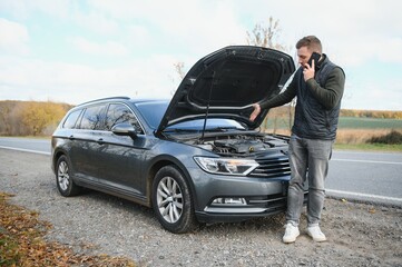 Wall Mural - Handsome young man calling for assistance with his car broken down by the roadside