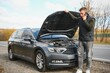 © Serhii - Man repairing a broken car by the road. Man having trouble with his broken car on the highway roadside. Man looking under the car hood. Car breaks down on the autobahn. Roadside assistance concept.