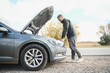 © Serhii - Man repairing a broken car by the road. Man having trouble with his broken car on the highway roadside. Man looking under the car hood. Car breaks down on the autobahn. Roadside assistance concept.