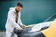 © Serhii - Man Holding Power Charging Cable For Electric Car In Outdoor Car Park. And he s going to connect the car to the charging station in the parking lot near the shopping center