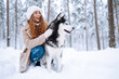 © maxbelchenko - Happy woman walking her dog in the winter and both explore the snow together in playful mood. Friendship, pet and human.