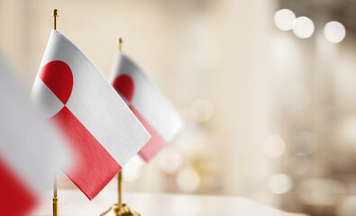 Small flags of the Greenland on an abstract blurry background