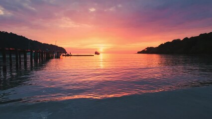 Wall Mural - Aerial view of colorful sunset over the tropical sea with wooden pier and sightseeing boat in summer