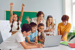 © Studio Romantic - Small group of happy cheerful excited smart school children have interesting class, look at laptop computer on desk, play game, win students competition together, celebrate amazing success and victory