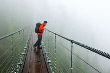 A Man Looks Over A Suspension Bridge On A Rainy Fall Day In Squamish, British Columbia.
