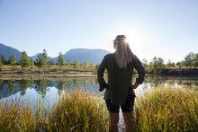 View Past Woman Greeting Sunrise Over Mountain Pond