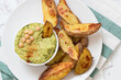 A bowl of spinach hummus dip with oven baked potato wedges