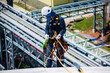 © chitsanupong - Top view male worker inspection wearing safety first harness rope safety line working at a high place on tank roof spherical gas