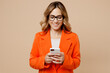 © ViDi Studio - Young fun confident employee business woman corporate lawyer 30s wears classic formal orange suit glasses work in office hold in hand use mobile cell phone isolated on plain beige background studio.