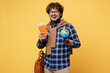 © ViDi Studio - Traveler happy Indian boy IT student wear casual clothes hold passport ticket globe Earth map isolated on yellow background. Tourist travel abroad for studying at university. Air flight trip concept.