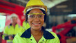 Portrait of woman looking camera at manufacturing special facility. Attractive women industrial engineer wear safety helmet, processes orders and products at manufacturing plant then look at camera.