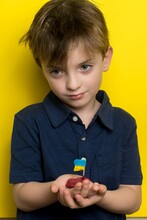 A Boy Of European Appearance Holds A Boat Made Of Plasticine With The Flag Of Ukraine In His Hands