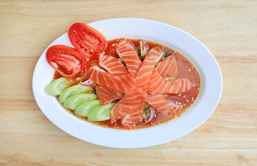 Canvas Print - Salmon spicy salad in dish on wood table background. Top view.