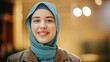 © Gorodenkoff - Portrait of Muslim Successful Businesswoman Wearing Hijab Looking at Camera and Smiling. Face Close Up of a Successful Empowered and Confident Arab Woman. Bokeh Blurred Background