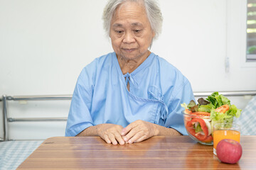 Wall Mural - Asian senior or elderly old lady woman patient eating Salmon steak breakfast with vegetable healthy food while sitting and hungry on bed in hospital.