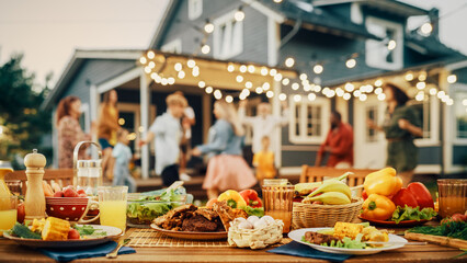 Wall Mural - Outdoors Dinner Table with Gorgeous-Looking Barbecue Meat, Fresh Vegetables and Salads. Happy Joyful People Dancing to Music, Celebrating and Having Fun in the Background on Home Porch.