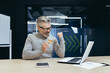 © Liubomir - Happy and smiling businessman in office making bank transfer and online purchase in online store, mature man holding bank credit card and using laptop, happy with choice.