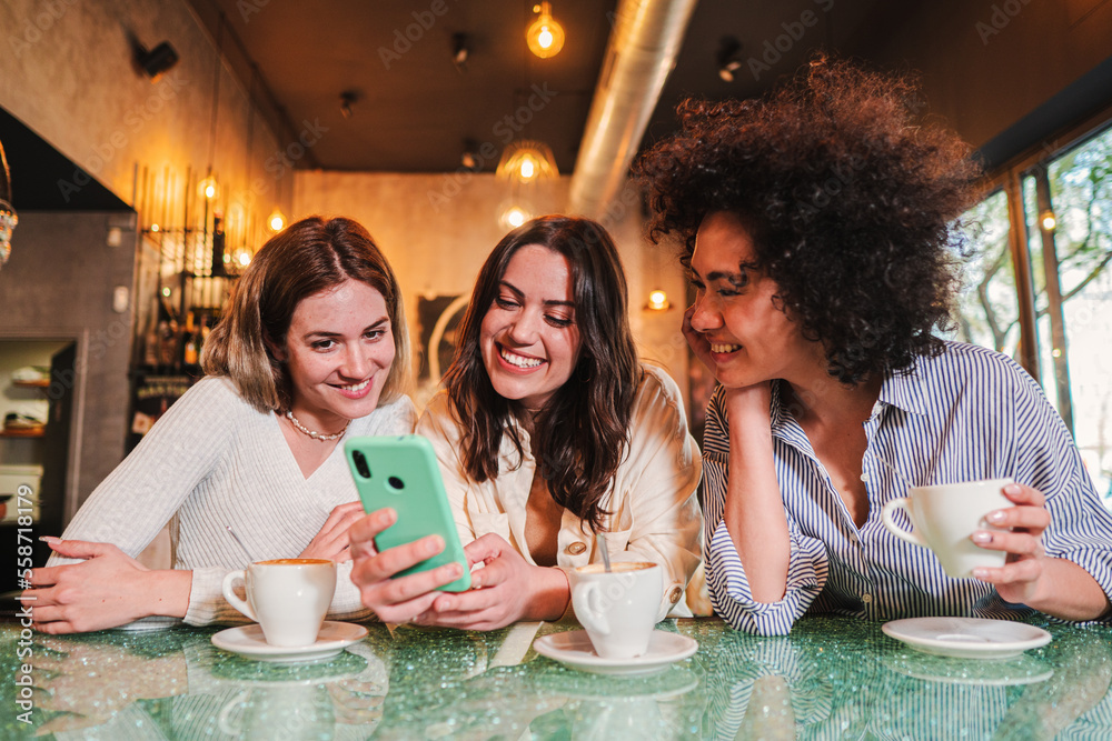 Three ladies smiling and having fun using a cellphone to send text ...
