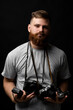 © Volodymyr - Photographer in grey t-shirt with a bunch of different vintage old film cameras looks into the camera. Close up portrait of man holding vintage camera. Film photography.