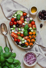 Flatlay Of A Greek Salad With Fresh Basil And Spoons On A Light Backdrop