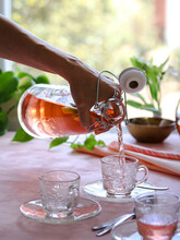 Pouring Orange Tea In Glass Tea Cups On A Pink Background