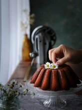 Citrus Bundt Cake Decorated With Flowers On A Glass Stand Next To The Window