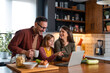 © Dorde - Young family watching tutorials on a laptop and about to prepare a delicious lunch with lots of fresh ingredients.