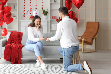 Wall Mural - Young man proposing to his beloved girlfriend at home on Valentine's Day