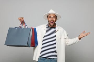 Poster - Happy African American man in hat with shopping bags on light grey background