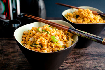 Wall Mural - Kimchi Fried Rice With Chopsticks Resting on the Bowls: Two bowls of Korean kimchi bokkeumbap made with fermented cabbage