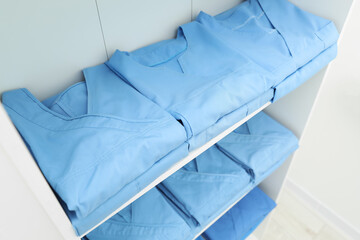 Light blue medical uniforms on white rack, above view