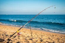 Red Fishing Pole Sitting On The Beach On A Nice Summer Day