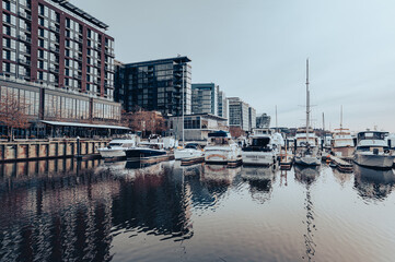 The Wharf reestablished Washington, DC, as a waterfront city and destination. Cloudy day at the marina, where boats are parked. Buildings in the back.