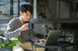 © wattana - Asian man freelancer drinking coffee and using laptop at coffee shop.
