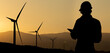 © scharfsinn86 - Silhouette of engineer with tablet computer and wind turbines at sunset
