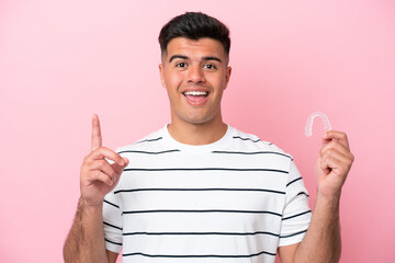 Wall Mural - Young caucasian man holding invisaling isolated on pink background pointing up a great idea