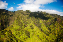 KAUAI, HAWAII, USA. Aerial Image Of Lush Green Mountain Slopes Under Soft Clouds And Blue Sky.