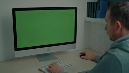 Aufkleber - guy wearing gray hoodie sitting at the desk playing online game on computer with green screen minimalist workplace at home or office