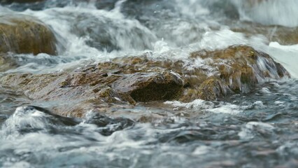 Wall Mural - Water flowing in spring river over small rock, closeup detail