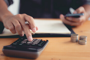 Fototapete - Investors are using a calculator to calculate investment costs while holding a smartphone.
