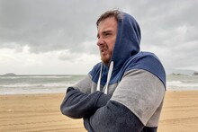 Portrait Of Unhappy Depressed Frozen Trembling Guy, Young Shivering From Cold Sad Upset Man On The Sea Beach, Suffering From Bad Weather On Summer Vacation 