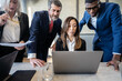© Vittorio Gravino - Group of multiracial businesspeople working on a laptop at a table in an office and discussing about new trend of financial markets