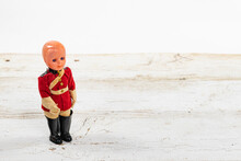 Vintage Plastic Molded Doll In A Military Uniform With A Shallow Depth Of Field And Copy Space On A White Wooden Table
