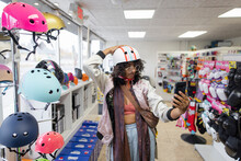 Woman Shopping, Trying On Helmet And Taking Selfie In Shop