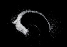 Spilled White Sea Salt On A Black Background. Clear Crystalline Pebbles On A Black Background. Salt Explosion.